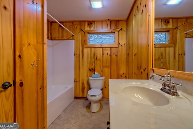 full bathroom with vanity, washtub / shower combination, wooden walls, tile patterned flooring, and toilet