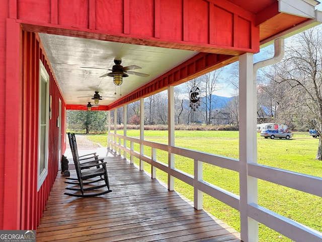 wooden terrace with ceiling fan, a yard, and covered porch