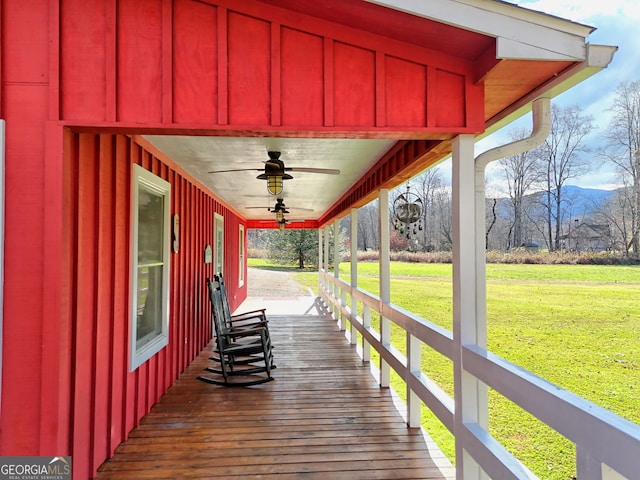 deck with ceiling fan, a yard, and covered porch