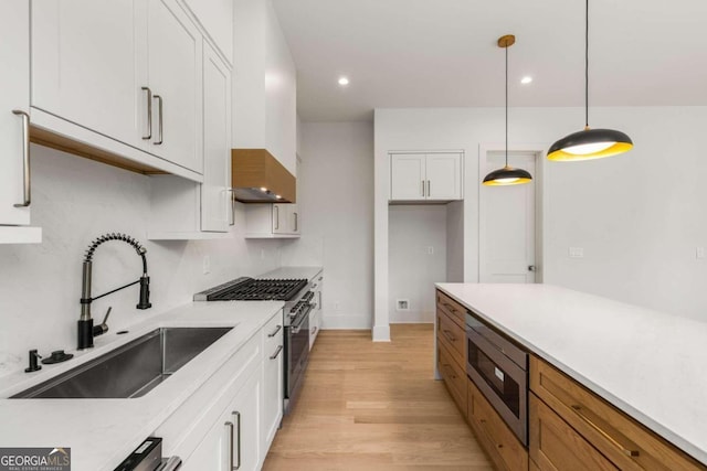 kitchen featuring appliances with stainless steel finishes, white cabinetry, hanging light fixtures, and sink