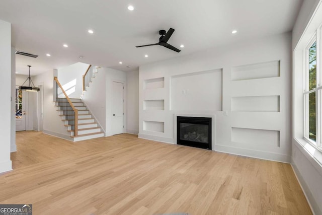 unfurnished living room with built in shelves, ceiling fan, light hardwood / wood-style flooring, and a healthy amount of sunlight