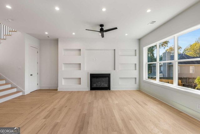 unfurnished living room featuring built in features, light hardwood / wood-style flooring, and ceiling fan