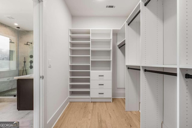 walk in closet with light hardwood / wood-style flooring