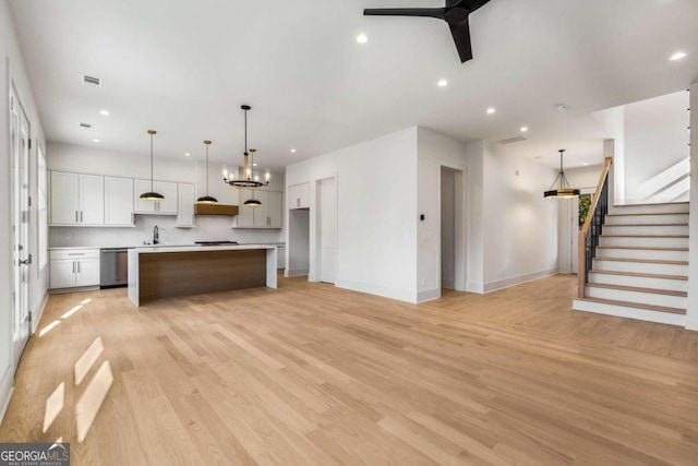 kitchen with white cabinetry, hanging light fixtures, a kitchen island, and light hardwood / wood-style floors