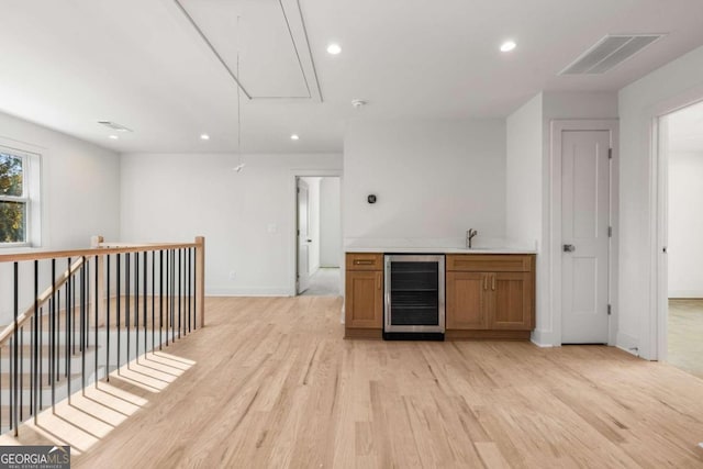 bar with wine cooler, sink, and light wood-type flooring