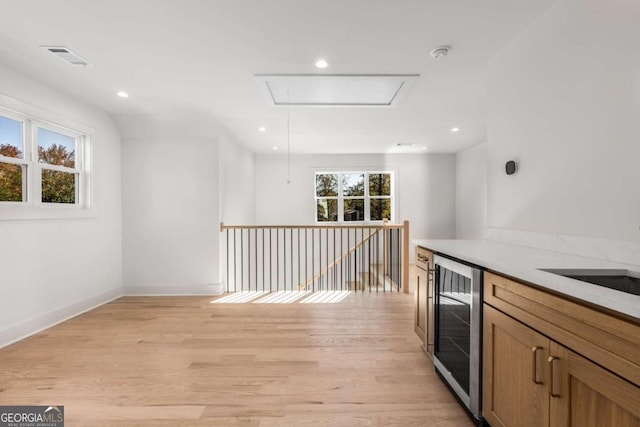 kitchen with wine cooler, a healthy amount of sunlight, and light hardwood / wood-style floors