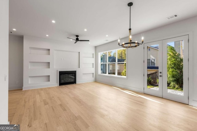 unfurnished living room featuring a wealth of natural light, built in features, and light wood-type flooring