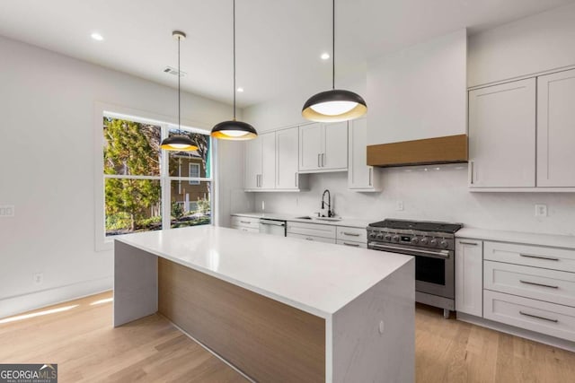 kitchen with a center island, white cabinets, sink, appliances with stainless steel finishes, and light hardwood / wood-style floors