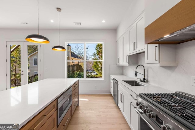 kitchen featuring white cabinets, custom exhaust hood, a healthy amount of sunlight, and appliances with stainless steel finishes