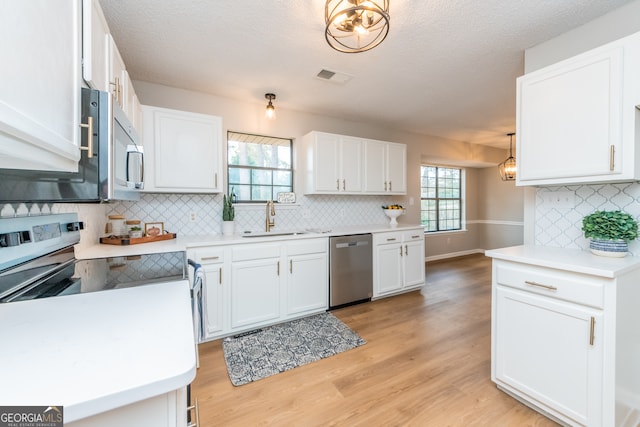 kitchen with stainless steel appliances, white cabinetry, a healthy amount of sunlight, and sink