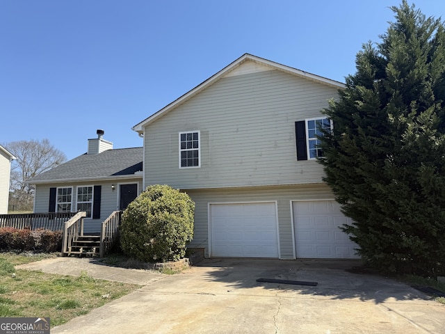 view of front facade featuring a wooden deck, an attached garage, a chimney, and driveway