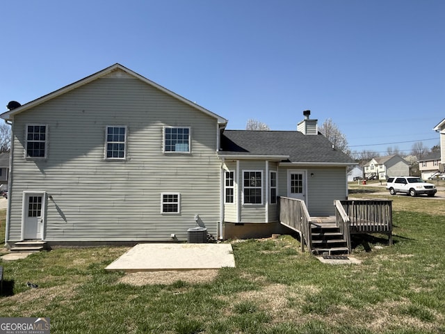 rear view of property with a deck, a lawn, roof with shingles, and a chimney