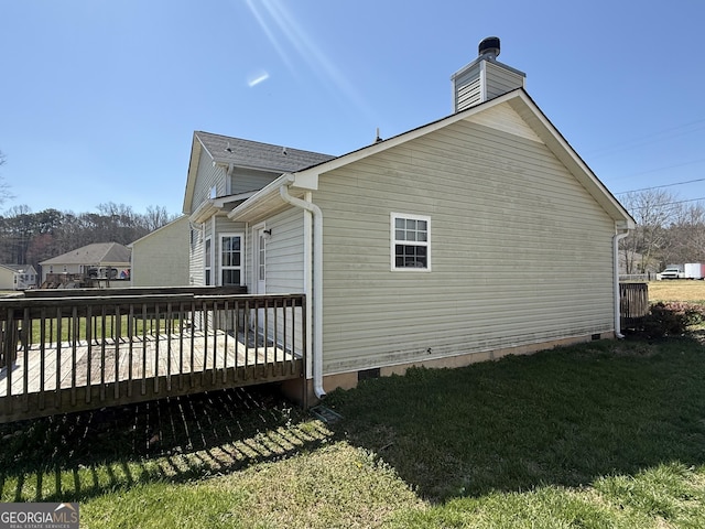 view of side of property featuring crawl space, a lawn, a chimney, and a wooden deck