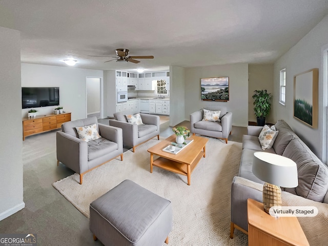 living room featuring ceiling fan, sink, light carpet, and a wealth of natural light