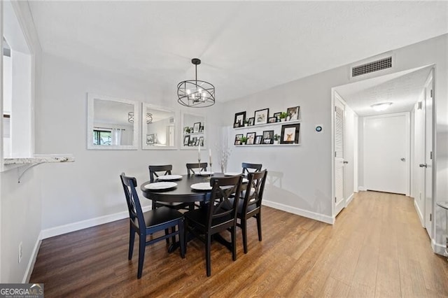 dining area with wood-type flooring and a notable chandelier