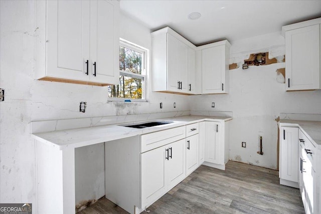 kitchen featuring white cabinets, light stone counters, and light hardwood / wood-style flooring