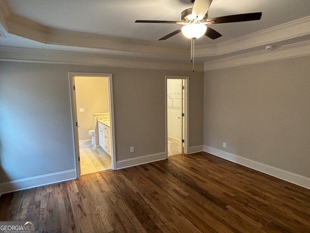 unfurnished bedroom with a walk in closet, ceiling fan, hardwood / wood-style floors, and ornamental molding