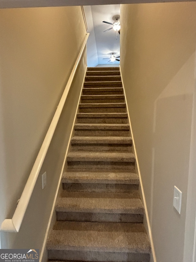 stairway featuring ceiling fan