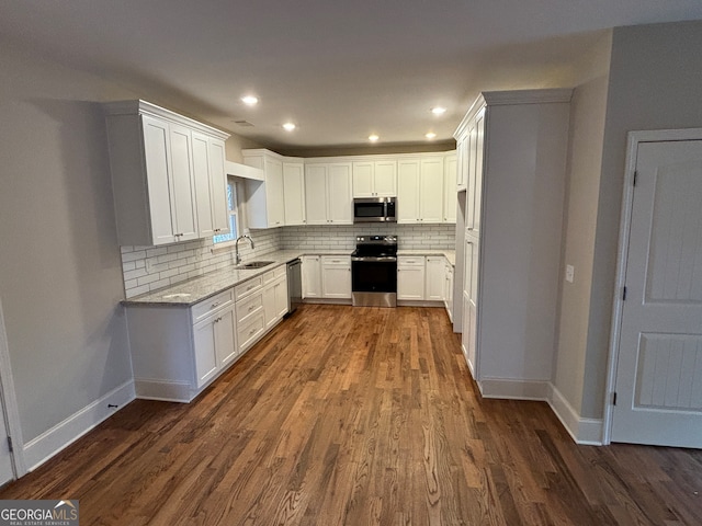 kitchen featuring sink, dark wood-type flooring, tasteful backsplash, white cabinets, and appliances with stainless steel finishes