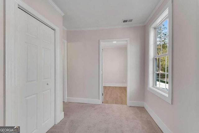 hallway featuring crown molding, a wealth of natural light, and light carpet