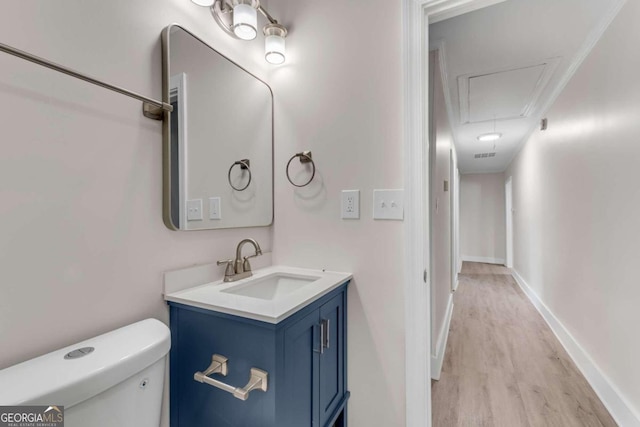 bathroom with crown molding, vanity, wood-type flooring, and toilet