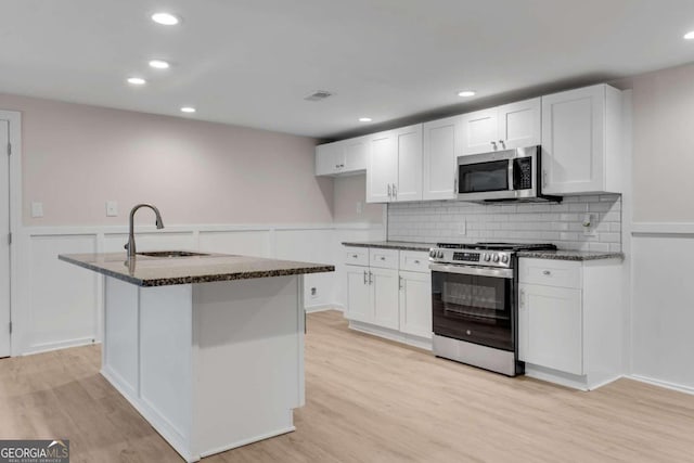 kitchen featuring white cabinets, light wood-type flooring, stainless steel appliances, and sink