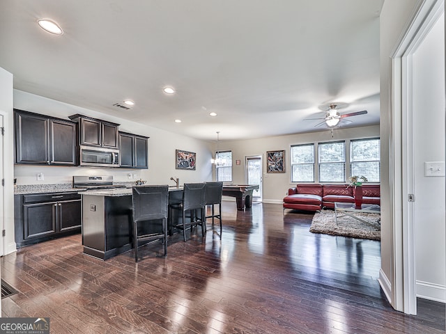 kitchen with a kitchen island with sink, dark wood-type flooring, hanging light fixtures, billiards, and appliances with stainless steel finishes