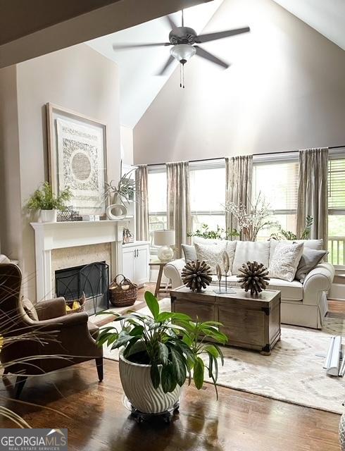 interior space with a fireplace, high vaulted ceiling, ceiling fan, and dark wood-type flooring