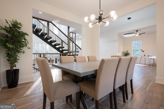 dining area featuring ceiling fan with notable chandelier and wood-type flooring