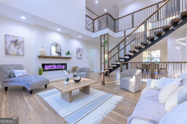 living room with light wood-type flooring and a towering ceiling