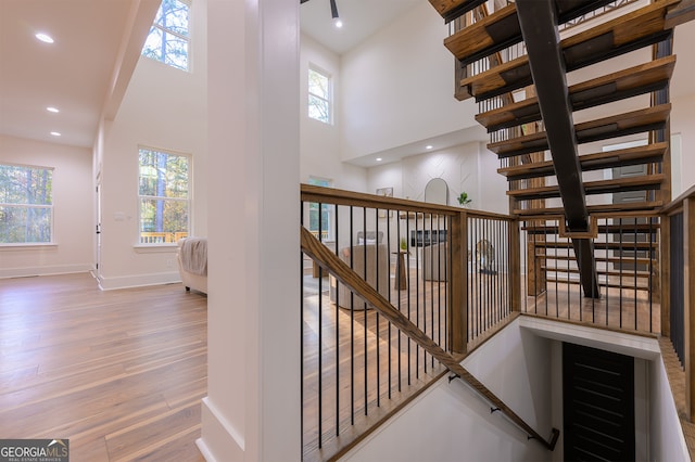 stairway featuring plenty of natural light, a towering ceiling, and wood-type flooring