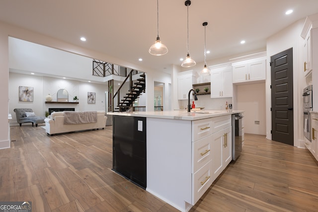 kitchen featuring white cabinetry, a kitchen island with sink, decorative light fixtures, and hardwood / wood-style flooring