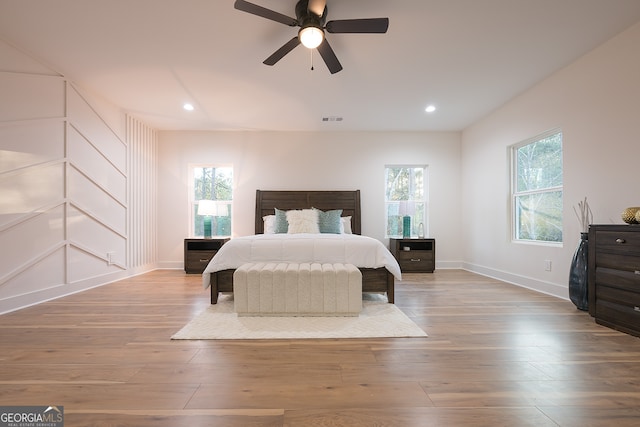 bedroom with ceiling fan, light wood-type flooring, and multiple windows