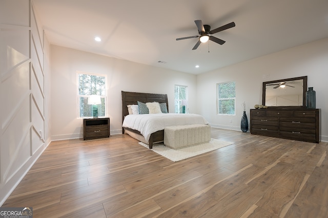 bedroom featuring hardwood / wood-style floors, ceiling fan, and multiple windows