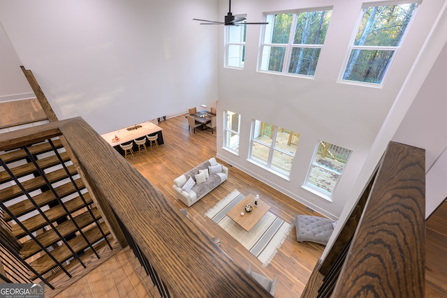 living room with hardwood / wood-style floors, ceiling fan, and a high ceiling