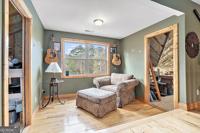 sitting room with light wood-type flooring and a textured ceiling