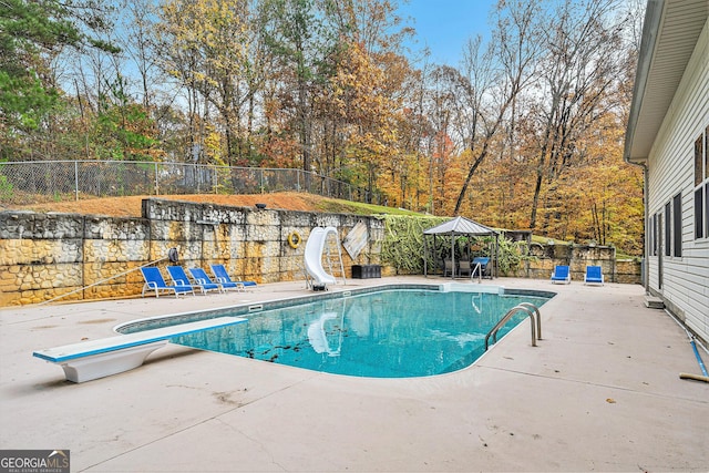 view of swimming pool featuring a diving board, a patio area, and a water slide