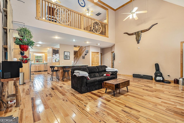 living room featuring ceiling fan, light hardwood / wood-style floors, crown molding, and high vaulted ceiling