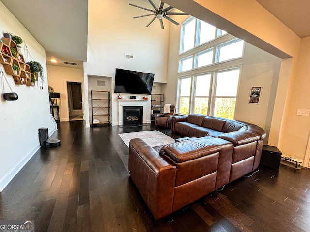 living room with ceiling fan, dark wood-type flooring, and a high ceiling