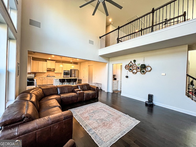 living room with ceiling fan, dark hardwood / wood-style floors, and a towering ceiling