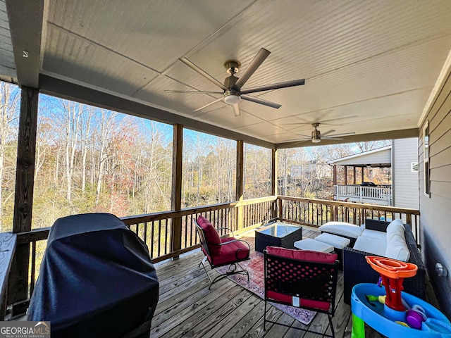 wooden deck with an outdoor hangout area, grilling area, and ceiling fan