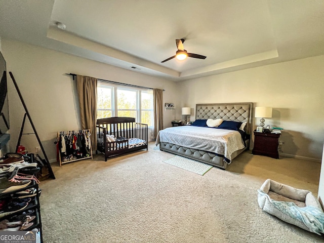 bedroom with carpet, a raised ceiling, and ceiling fan