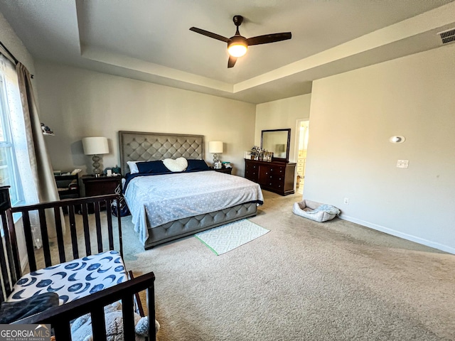 carpeted bedroom with a tray ceiling and ceiling fan