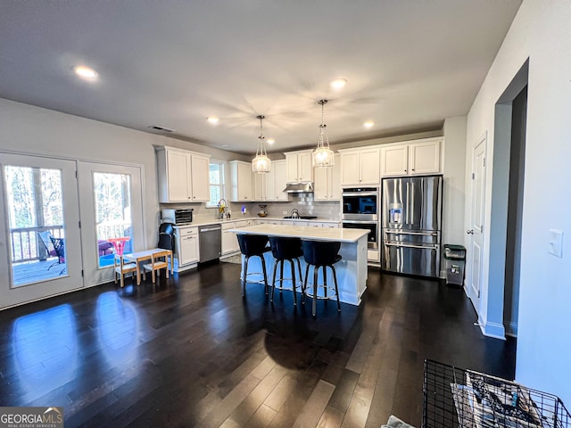 kitchen featuring white cabinetry, a kitchen island, hanging light fixtures, and appliances with stainless steel finishes