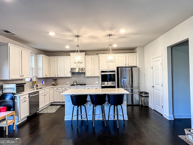 kitchen featuring a center island, white cabinets, decorative light fixtures, and appliances with stainless steel finishes