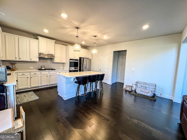 kitchen with white cabinets, decorative light fixtures, stainless steel appliances, and a kitchen island