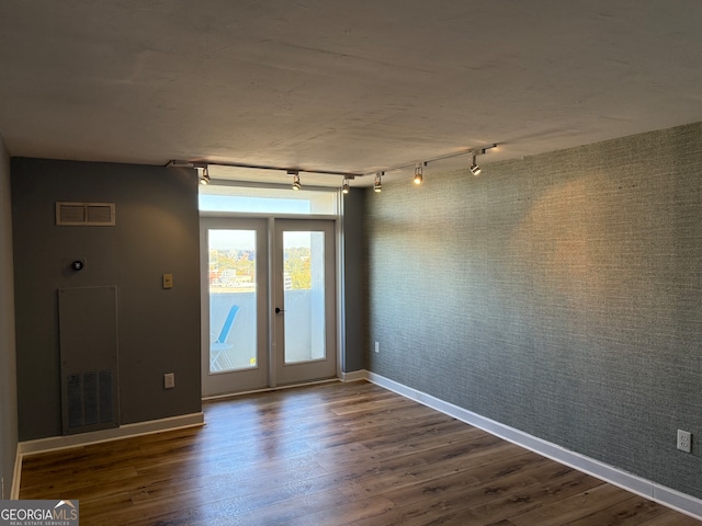 spare room featuring dark hardwood / wood-style flooring and track lighting