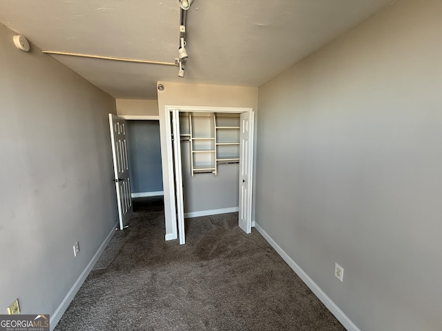 unfurnished bedroom featuring dark carpet and a closet