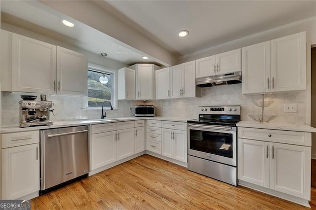 kitchen with white cabinets, sink, tasteful backsplash, light hardwood / wood-style floors, and stainless steel appliances