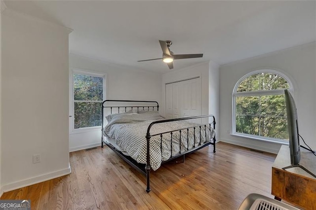 bedroom with a closet, light hardwood / wood-style floors, multiple windows, and ceiling fan